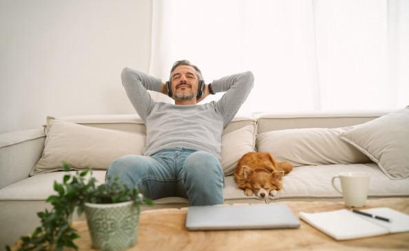 Mann hört Musik und entspannt neben seinem Hund auf dem Sofa | Der Dämmstoff | Foto von zGel auf istockphoto.com