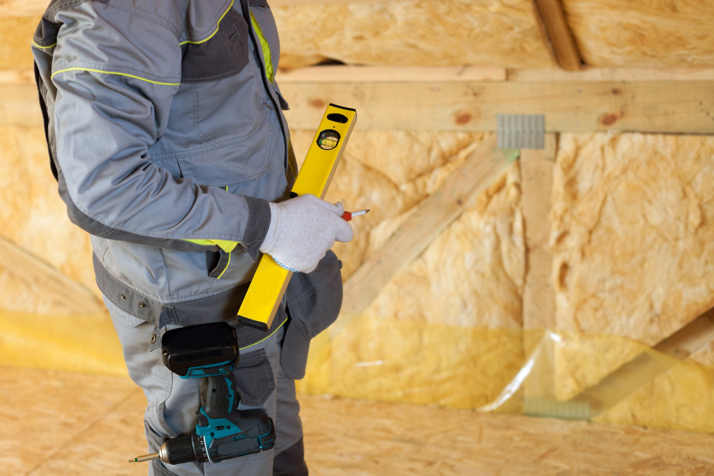 Handwerker auf dem Dachboden dämmt das Dach mit Mineralwolle | Der Dämmstoff | Foto von brizmaker – istockphoto.com