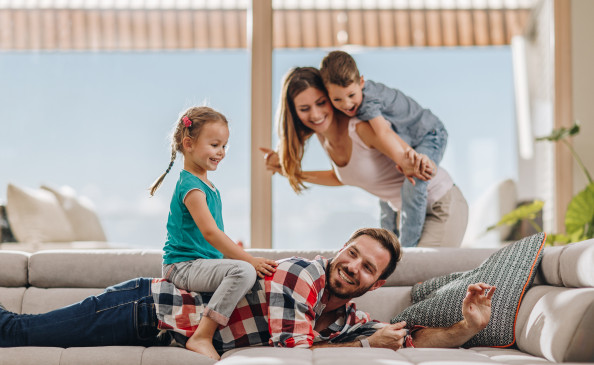 Junge Familie spielt im Wohnzimmer | Behaglichkeit zu Hause im Sommer | Der Dämmstoff | Foto von skynesher – istockphoto.com