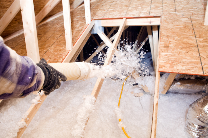 Einblasdämmung im Dachraum: Der lose Dämmstoff aus Mineralwolle wird über den Deckenbalken verteilt. | Der Dämmstoff | Foto von FMI / BanksPhotos - iStock